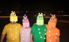 three people wearing paper hats with eyes and nose on their heads, standing next to each other