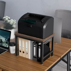 a laptop computer sitting on top of a wooden desk next to a printer and other office supplies