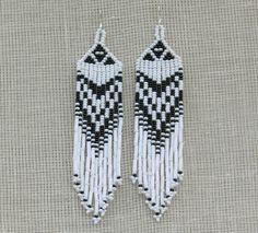 two white and black beaded earrings sitting on top of a piece of cloth next to each other