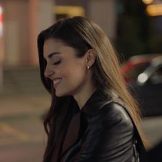 a young woman smiles as she walks down the street at night with her eyes closed