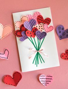 valentine's day card with paper hearts and flowers on pink background, surrounded by cut out hearts