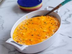 a casserole dish on a marble table with three colorful plates in the background