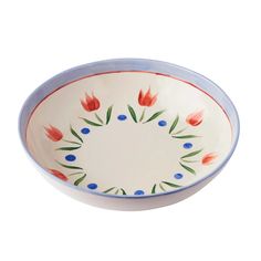 a blue and white bowl with red flowers on the rim, sitting in front of a white background