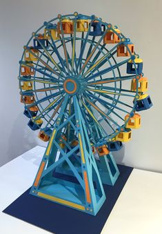 a colorful ferris wheel sitting on top of a white table next to a blue wall