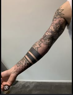 a man's arm with flowers and stripes tattooed on the forearm, in black and grey