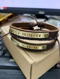 two leather bracelets sitting on top of a laptop