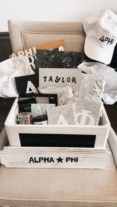 a white box filled with personal items sitting on top of a couch next to a hat