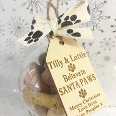 a glass jar filled with dog treats and a tag that says tiny & lottie believe in santa paws