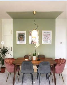 a dining room table with chairs and pictures on the wall above it, along with potted plants