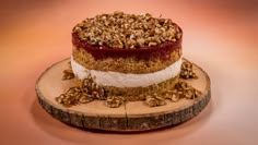 a piece of cake sitting on top of a wooden plate covered in nuts and crumbles