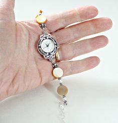 "Mother of pearl sterling silver bracelet watch is handcrafted. Would make a great 50th birthday gift for Mom or Mothers Day gift from son or daughter! Beige shell mother of pearl showcased with white freshwater pearls and Bali sterling silver. Watch is adjustable from 6 1/4\" to 8 1/2\". Metaphysical meaning of Mother of Pearl: Mother of Pearl, considered a protection stone, is a stress relieving stone; relaxing, soothing and calming to the emotions. It stimulates our intuition, imagination, se Silver Jubilee Bracelet As A Gift, Timeless Silver Pearl Jubilee Bracelet, Silver Jewelry And Watches With Bracelet Strap As Gift, Silver Watches With Jubilee Bracelet As Gift, Silver Watches With Jubilee Bracelet For Gift, Timeless Round Pearl Bracelet As Gift, Handmade Silver Pearl Bracelet Gift, Vintage Silver Pearl Bracelet Gift, Silver Bracelet Strap Jewelry For Anniversary