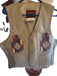 This western Indian vest size 46 is my brother’s western vest . He told me he never wore it & can tell it hasn’t been worn It is a Genuine chimayo handwoven blanket The colors tan , blue , rust , black , brown & black Measurements is in chest - 46 Shoulders - 14” Length - 22” Has 2 front pockets that slant toward the opening not downward Dry clean only This would be a great Christmas present for your man or woman Made in the USA All silver buttons are attached to vest Indian Vest, Handwoven Blanket, Western Vest, Hand Woven Blanket, Silver Buttons, Your Man, My Brother, Vest Jacket, Wool Blend