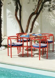 an outdoor table and chairs next to a pool