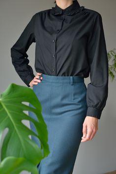 Frill-trim-collar cotton blend shirt in black. Shirt in an airy cotton blend weave with frill trimmed collar. Regular fit with buttons down the front, cuffed sleeves and gently rounded hem. - Closure - button up - Great vintage condition - Regular fit BRAND: Carat Made in Hong Kong MATERIAL: 65% Polyester 35% Cotton SIZE Marked as 42. Regular fit for S (small) size. MEASUREMENTS Shoulders: 41cm = 16,1" Chest: 50cm = 19,7" Waist: 48cm = 18,9" Length: 64cm = 25,2" Sleeve length: 60cm = 23,6" ✂ --- Slim Fit Workwear Blouse With Fold Down Collar, Workwear Top With Ruffled Collar And Buttons, Classic Office Shirt With Ruffled Collar, Classic Shirt With Ruffled Collar For Office, Workwear Blouse With Ruffled Collar And Buttons, Workwear Blouse With Buttons And Ruffled Collar, Cotton Blouse With Ruffled Collar For Work, Cotton Workwear Shirt With Ruffled Collar, Classic Shirt With Ruffled Collar For Work