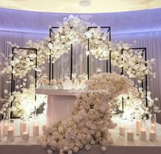 a table topped with lots of white flowers next to tall candles and chandeliers