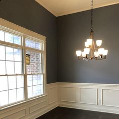 a chandelier hanging from the ceiling in a room with gray walls and wood floors