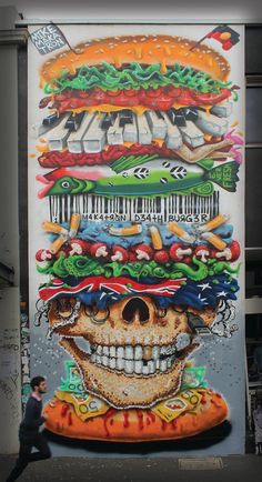 a large mural of a giant hamburger with a skull on it's face and many different toppings