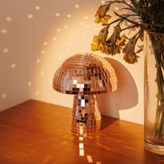 a vase filled with yellow flowers sitting on top of a wooden table next to a lamp