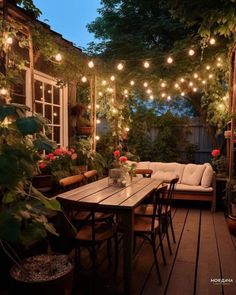 an outdoor patio with lights strung from the ceiling and potted plants on the table