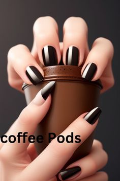 a woman's hand holding a cup with black and white stripes on it that says coffee pods