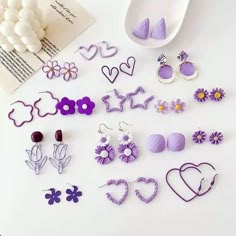 several pairs of earrings are displayed on a table next to a book and flower vase