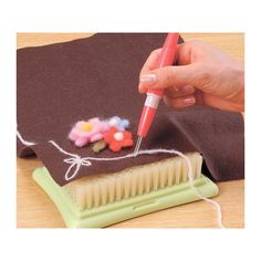 a person is using a brush to decorate something on a piece of cloth with yarn