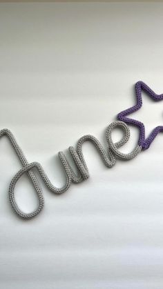 the word dunne spelled with purple and silver glitter stars on a white wall behind it