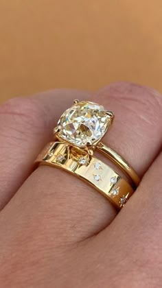 a woman's hand with two gold rings on her fingers and an engagement ring in the middle