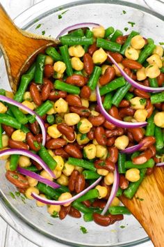 beans, onions and green beans in a bowl with a wooden spoon on the side