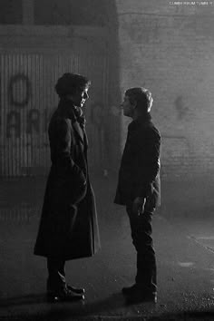 two men standing next to each other in the dark