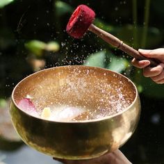 a person is throwing sand into a bowl with a wooden stick in the air and a red object sticking out of it