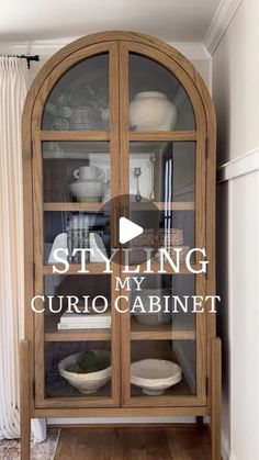 a wooden china cabinet with glass doors in the middle and words saying styling my curio cabinet