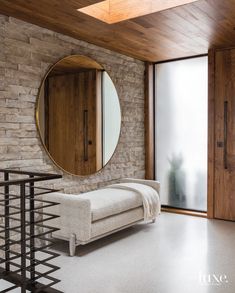 a living room with brick walls and a round mirror on the wall next to a bench