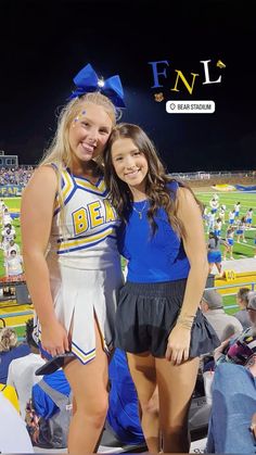 two cheerleaders posing for a photo at a football game