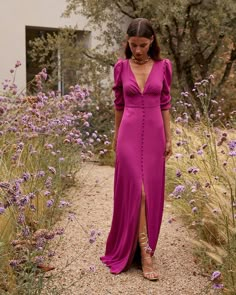 a woman in a long purple dress standing on a path