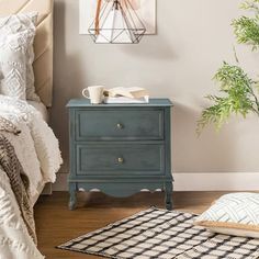 a bedroom with a bed, nightstand and plant on the side table in front of it