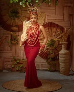 a woman in a red dress and headpiece standing on top of a round mat