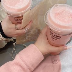 two cups of ice cream are being held by someone's hands in pink sweaters