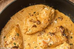 some chicken is in a yellow sauce in a skillet on a wooden table top