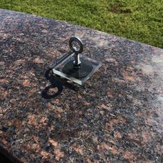 a marble table with an iron ring on it and grass in the backround