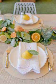 the table is set with plates, silverware and lemons on top of napkins