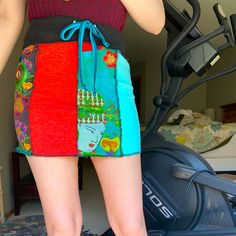 a woman standing in front of a machine with her hand on her hip and wearing colorful shorts