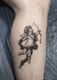 a man with a bow and arrow tattoo on his leg is holding an arrow in the shape of a cupid