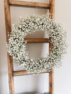 a white wreath is hanging on a ladder