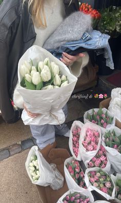 a woman holding flowers in her hands on the ground next to other bags and boxes