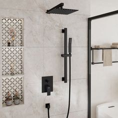 a bathroom with a white toilet and black shower faucet next to a tiled wall