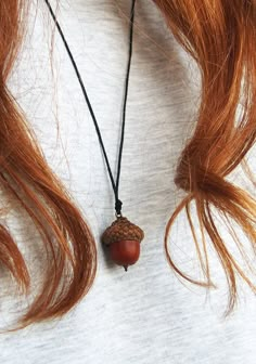 a woman wearing a necklace with an acorn on it