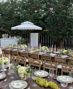 an outdoor dining table set up with plates, glasses and fruit on it for a formal function