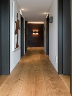 an empty hallway with wood flooring and artwork hanging on the wall above it's doors