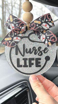 a nurse life ornament hanging from the dashboard of a car with a bow on it